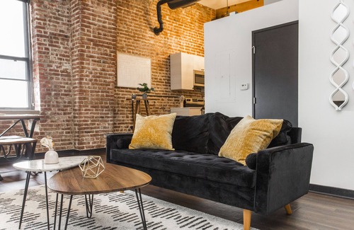 Kansas City Apartment | Exposed brick, wood beams, & chic touches give this loft serious style. Enjoy skyline views from the rooftop, a full kitchen with coffee bar, king bed, on-site gym, & quick access to the free KC streetcar. Walk to shops/dining, and the City Market!
