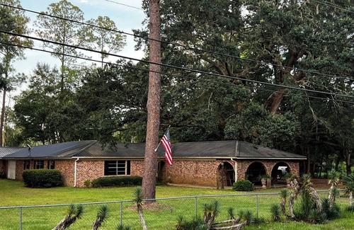 Moss Point House | Large fenced in home under a giant, moss covered, southern oak tree.