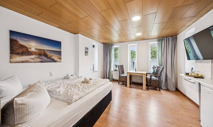 Wilhelmshaven Hotel | Cozy double room, seating area, flat-screen TV, and modern bathroom with shower. Ideal for couples and short stays – enjoy a relaxed atmosphere with warm wood accents and coastal charm.