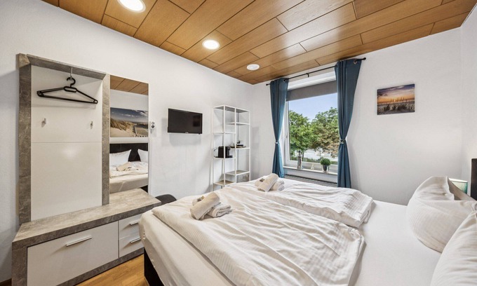 Wilhelmshaven Hotel | Cozy double room, flat-screen TV, and modern bathroom with shower. Ideal for couples and short stays – enjoy a relaxed atmosphere with warm wood accents and coastal charm.